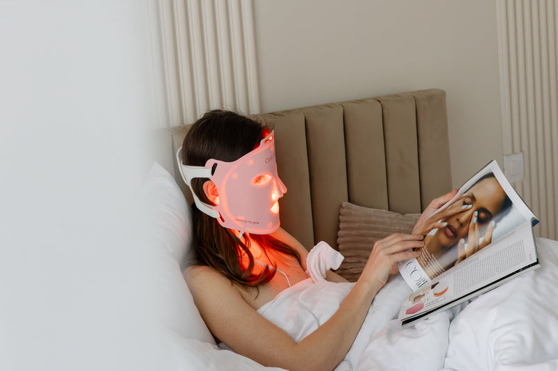 Lady with CelluVIVLED Face Mask on the face relaxing with a magazine in the hand 