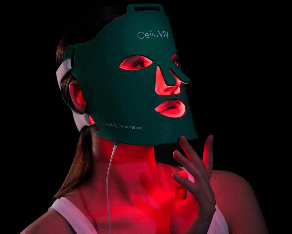 Person wearing a green LED face and neck mask with visible branding on a black background