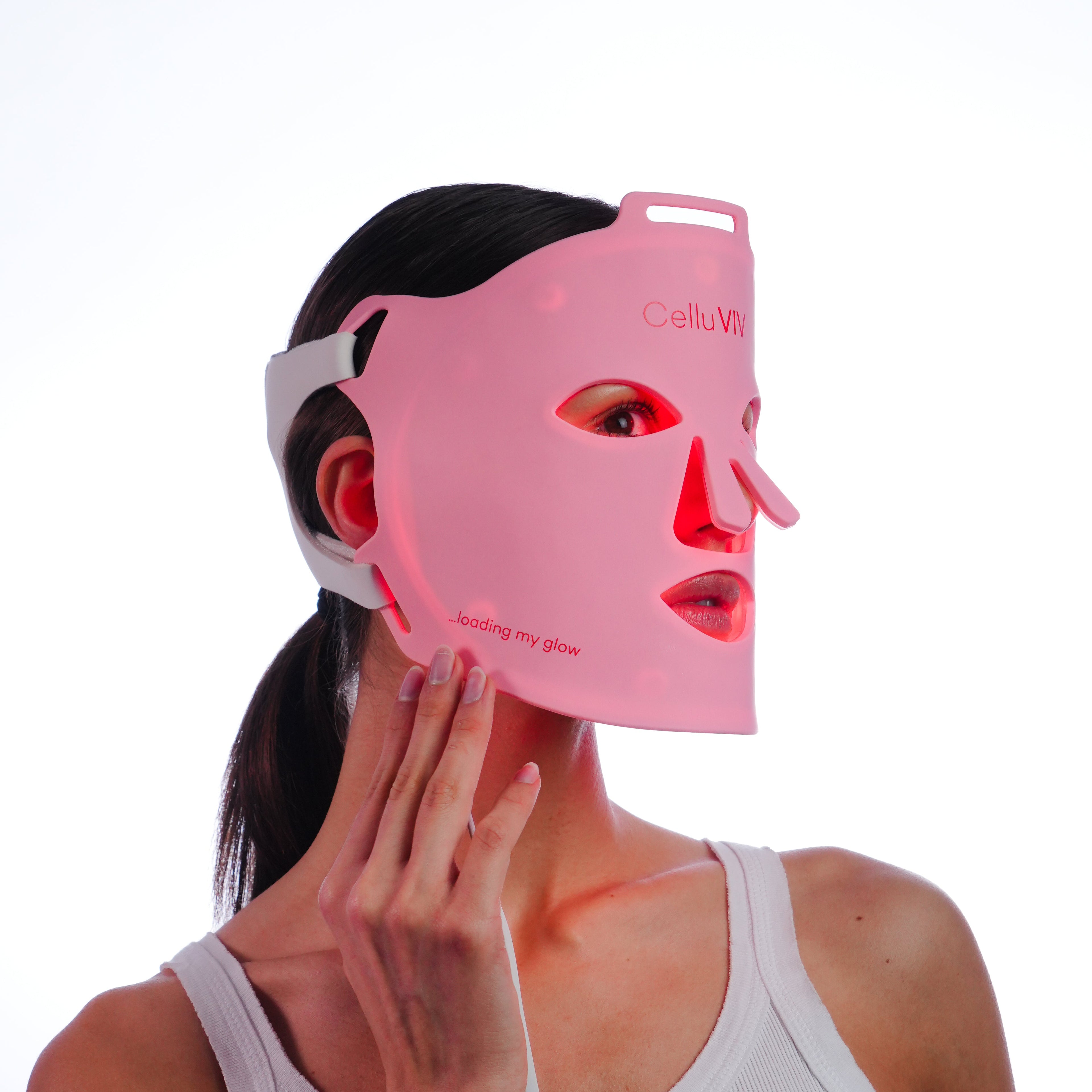 Person wearing a pink LED face mask on a white background