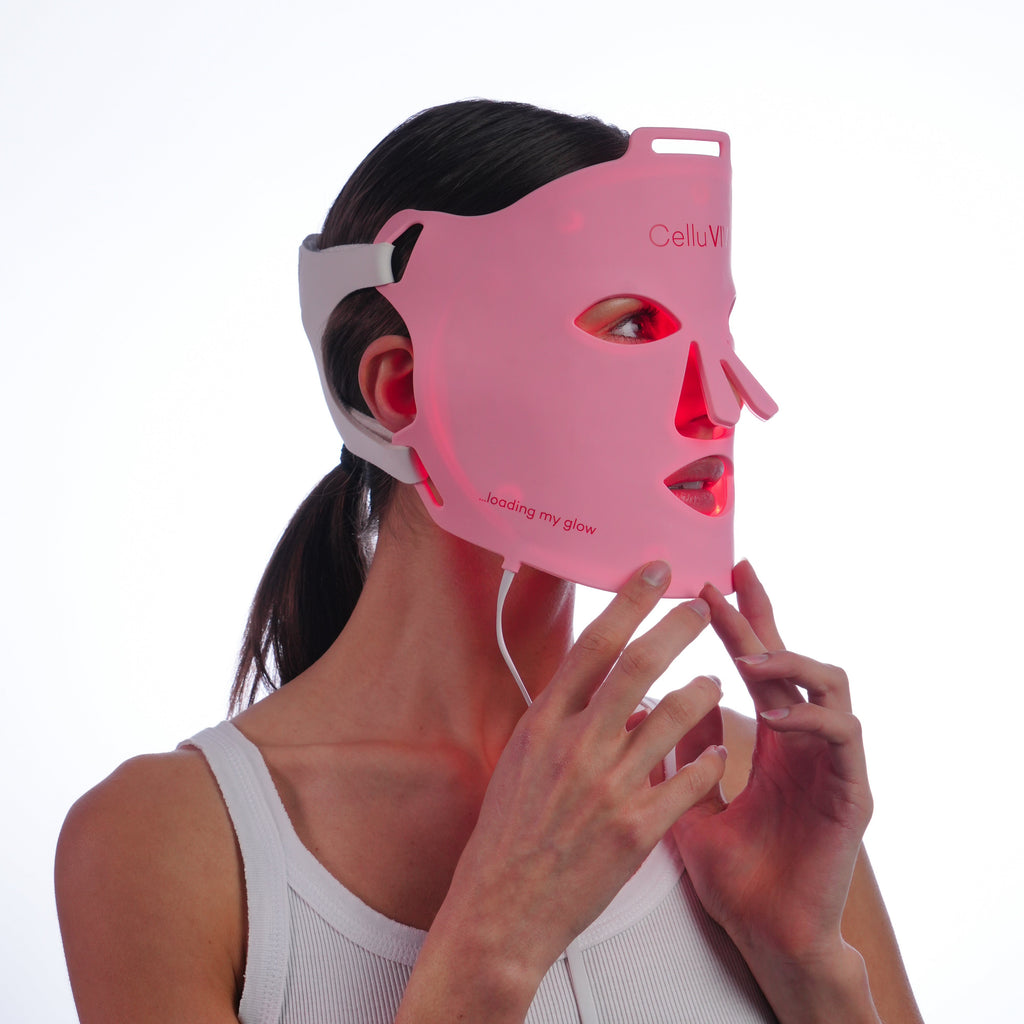 Woman wearing a pink CelluVIV  LED face mask on a white background